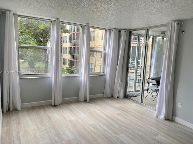 unfurnished room featuring light wood-type flooring and a textured ceiling