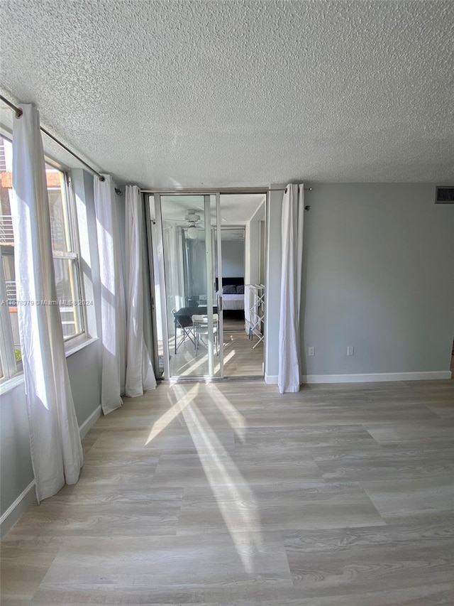 unfurnished room featuring a textured ceiling and light hardwood / wood-style floors