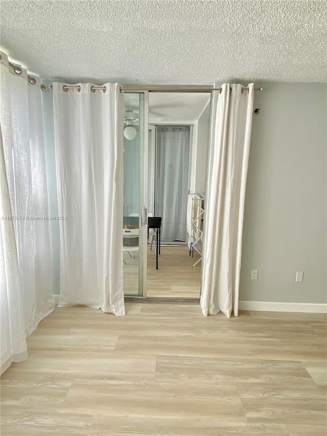 hall with a textured ceiling and light wood-type flooring