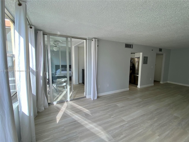 unfurnished room with light hardwood / wood-style flooring and a textured ceiling