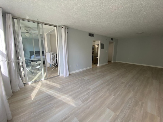 empty room featuring ceiling fan, light hardwood / wood-style flooring, and a textured ceiling