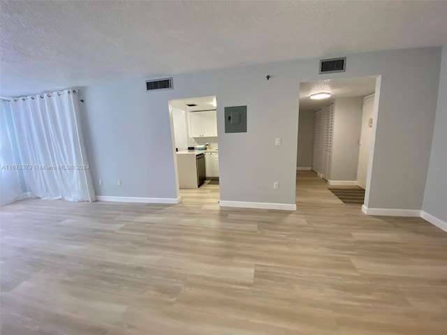 unfurnished room with light wood-type flooring, a textured ceiling, and electric panel