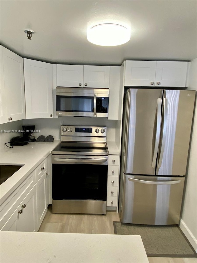 kitchen featuring white cabinets, appliances with stainless steel finishes, light wood-type flooring, and sink