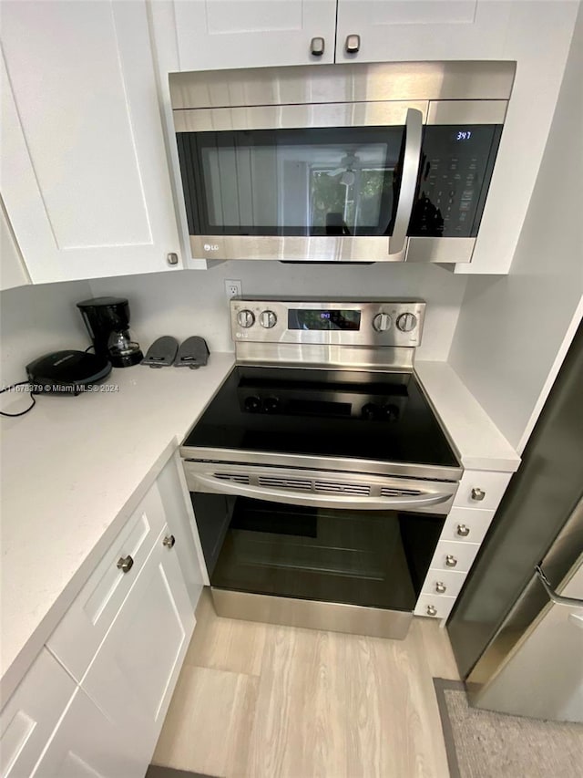 kitchen with white cabinetry, light hardwood / wood-style floors, and appliances with stainless steel finishes