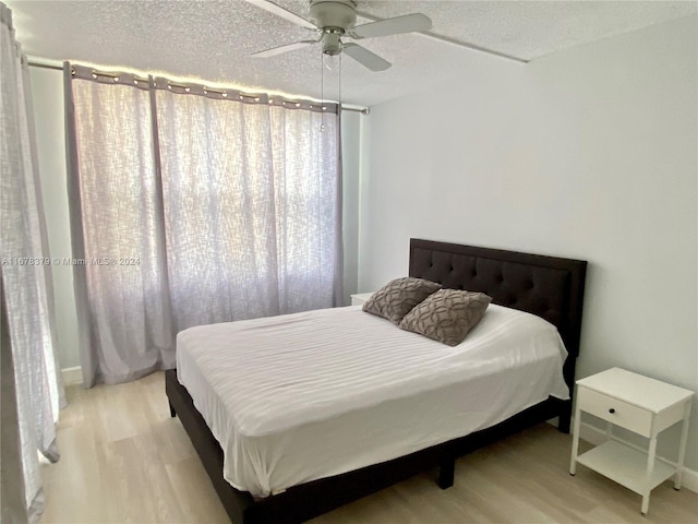 bedroom with ceiling fan, light wood-type flooring, and a textured ceiling