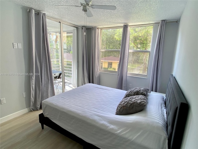 bedroom featuring access to exterior, a textured ceiling, light hardwood / wood-style flooring, and ceiling fan