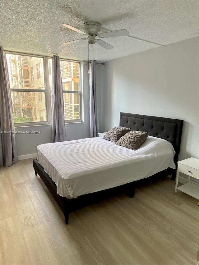 bedroom featuring ceiling fan, a textured ceiling, and light wood-type flooring