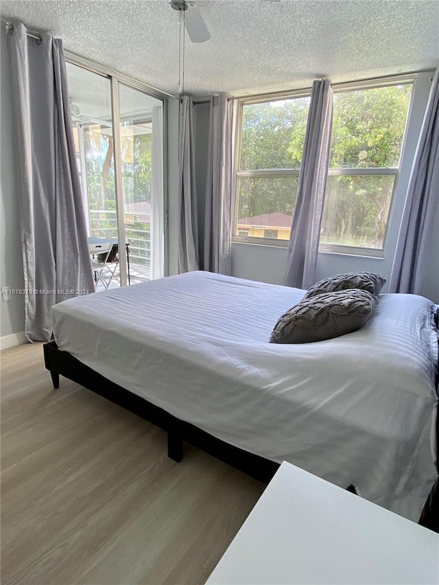 bedroom with ceiling fan, wood-type flooring, and a textured ceiling