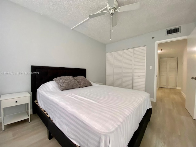 bedroom featuring ceiling fan, a closet, a textured ceiling, and light wood-type flooring