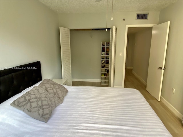 bedroom featuring light hardwood / wood-style floors, a textured ceiling, and a closet