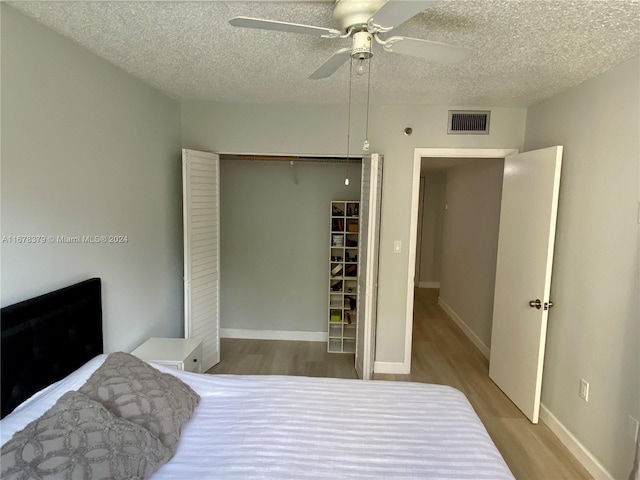 bedroom featuring ceiling fan, a closet, wood-type flooring, and a textured ceiling