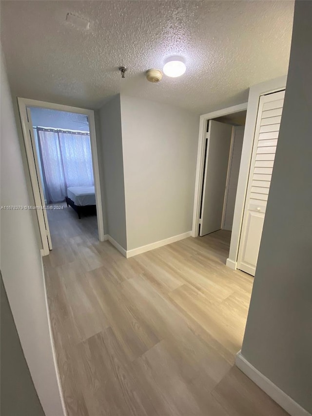 corridor featuring light hardwood / wood-style floors and a textured ceiling