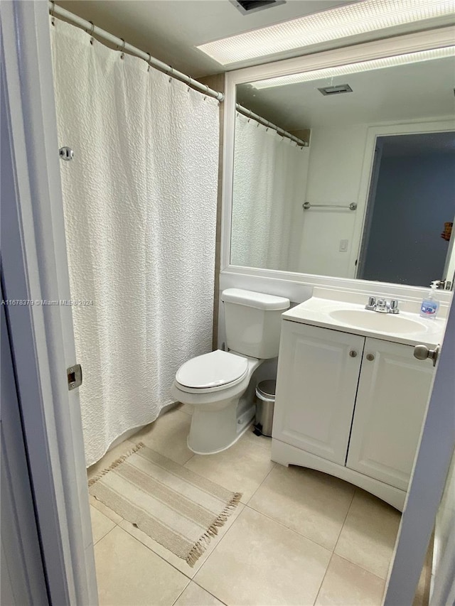 bathroom with toilet, vanity, and tile patterned floors