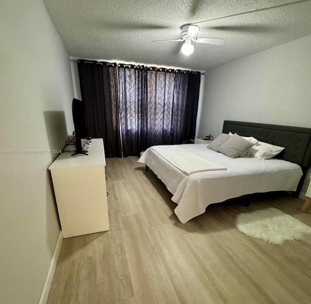 bedroom with ceiling fan, light wood-type flooring, and a textured ceiling