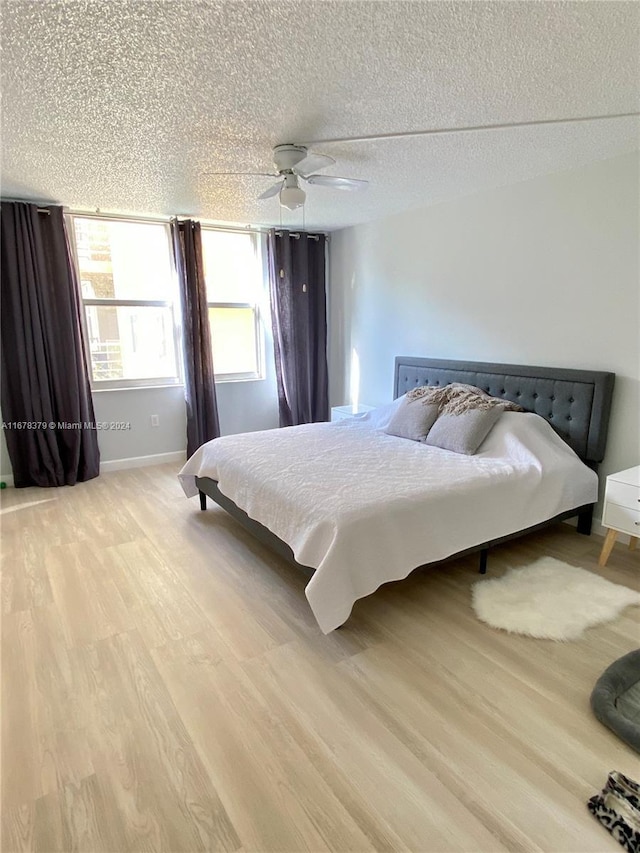 bedroom with ceiling fan, light hardwood / wood-style floors, and a textured ceiling