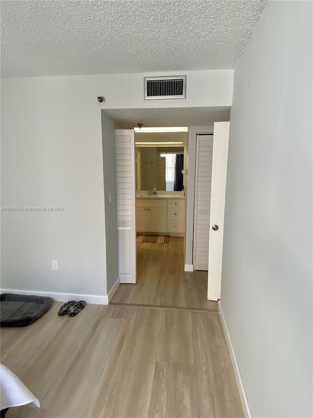 hallway featuring a textured ceiling, light hardwood / wood-style floors, and sink