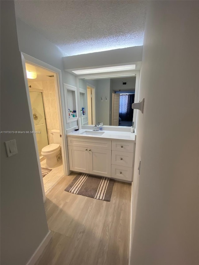 bathroom featuring vanity, a textured ceiling, hardwood / wood-style flooring, and walk in shower