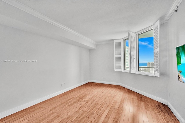 empty room featuring crown molding, hardwood / wood-style flooring, and a textured ceiling