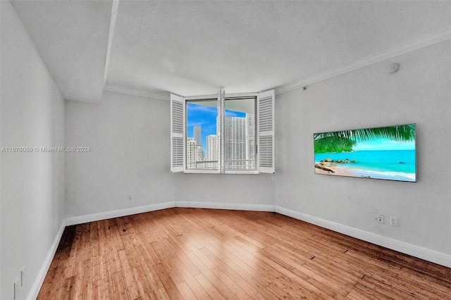 unfurnished room featuring ornamental molding, a textured ceiling, and wood-type flooring