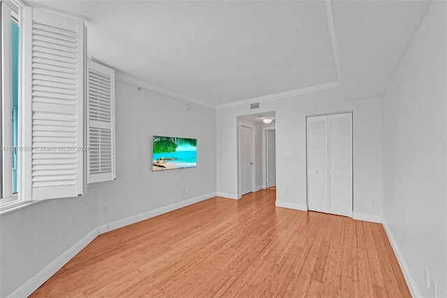 unfurnished living room featuring light hardwood / wood-style floors and crown molding