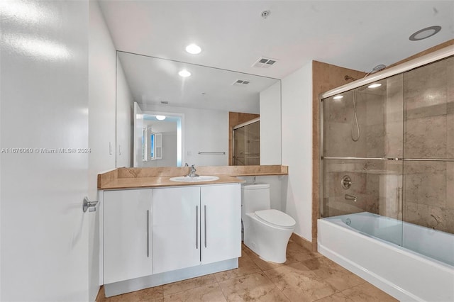 full bathroom featuring vanity, toilet, combined bath / shower with glass door, and tile patterned flooring