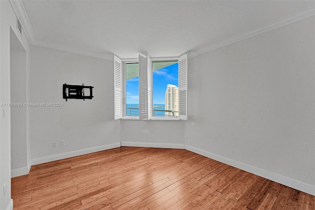 empty room with ornamental molding and light hardwood / wood-style flooring