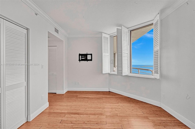 unfurnished room featuring light hardwood / wood-style floors, ornamental molding, and a textured ceiling