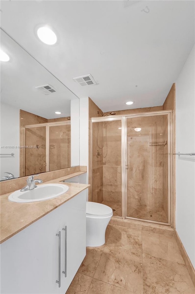 bathroom featuring vanity, a shower with shower door, and toilet