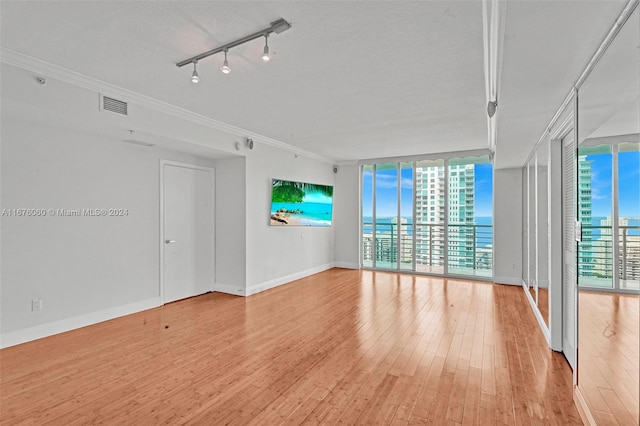 unfurnished living room with ornamental molding, a wall of windows, and light hardwood / wood-style flooring