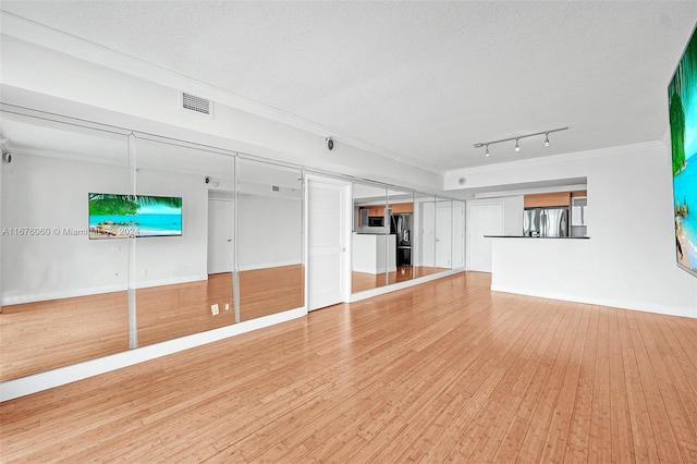 unfurnished living room with rail lighting, a textured ceiling, ornamental molding, and hardwood / wood-style floors