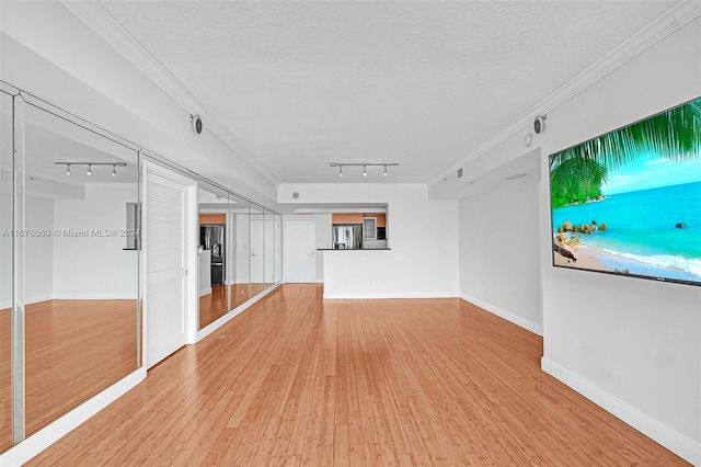 unfurnished living room featuring light hardwood / wood-style flooring, a textured ceiling, and track lighting