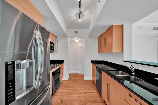 kitchen with sink, light hardwood / wood-style flooring, stainless steel appliances, and dark stone countertops