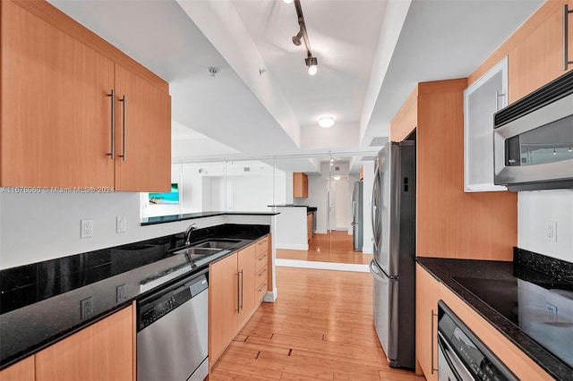 kitchen with track lighting, light hardwood / wood-style flooring, dark stone countertops, sink, and appliances with stainless steel finishes