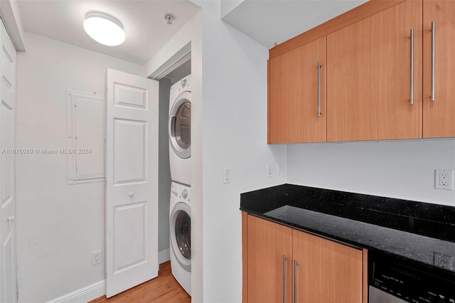 laundry area featuring stacked washer / dryer, electric panel, and light hardwood / wood-style flooring