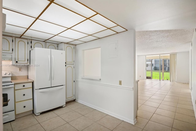 kitchen featuring a textured ceiling, light tile patterned floors, and white appliances