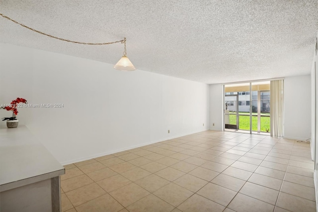 empty room with expansive windows, a textured ceiling, and light tile patterned flooring