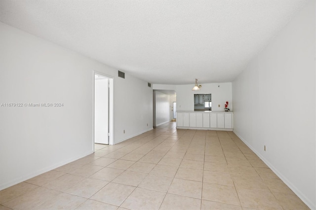 unfurnished living room with a textured ceiling and light tile patterned floors