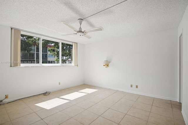 spare room featuring a textured ceiling, light tile patterned floors, and ceiling fan