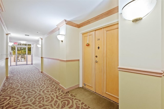 hallway featuring visible vents, crown molding, baseboards, and carpet floors