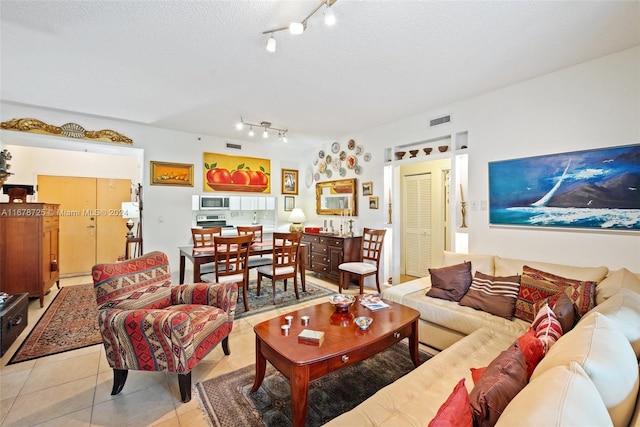 living room featuring a textured ceiling, rail lighting, and light tile patterned floors