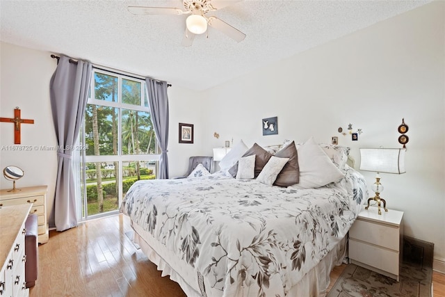 bedroom with a textured ceiling, light wood-type flooring, and ceiling fan