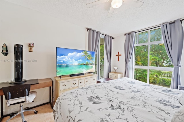 bedroom featuring multiple windows, a textured ceiling, light wood-type flooring, and ceiling fan