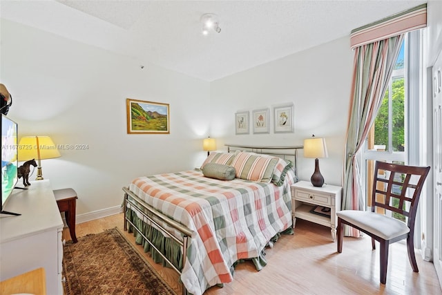 bedroom featuring a textured ceiling and light hardwood / wood-style flooring