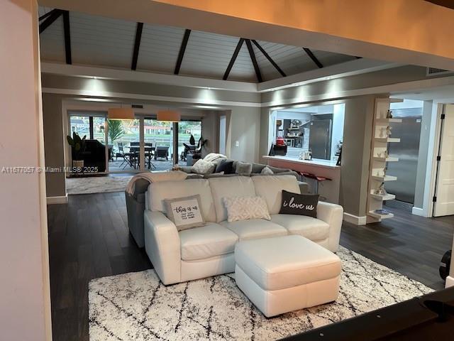 living area with baseboards, lofted ceiling, and wood finished floors