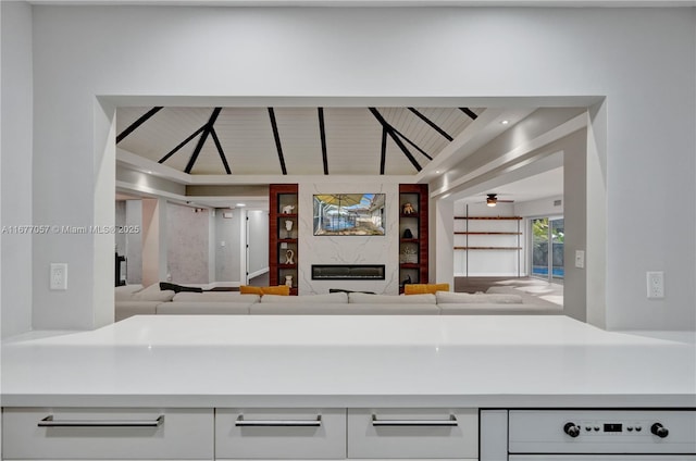 kitchen with vaulted ceiling, a ceiling fan, a premium fireplace, open floor plan, and light countertops
