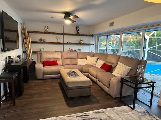 living room featuring wood finished floors, visible vents, a wealth of natural light, and a ceiling fan