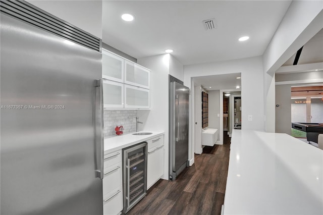 kitchen featuring high end refrigerator, white cabinets, dark wood-type flooring, and beverage cooler