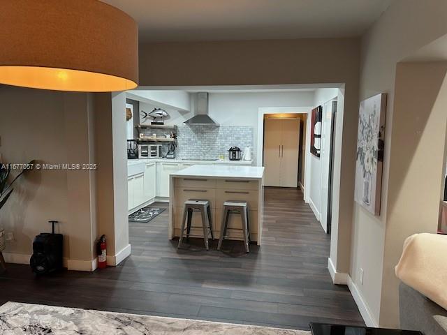 kitchen featuring a kitchen island, wall chimney exhaust hood, dark wood-style floors, and decorative backsplash