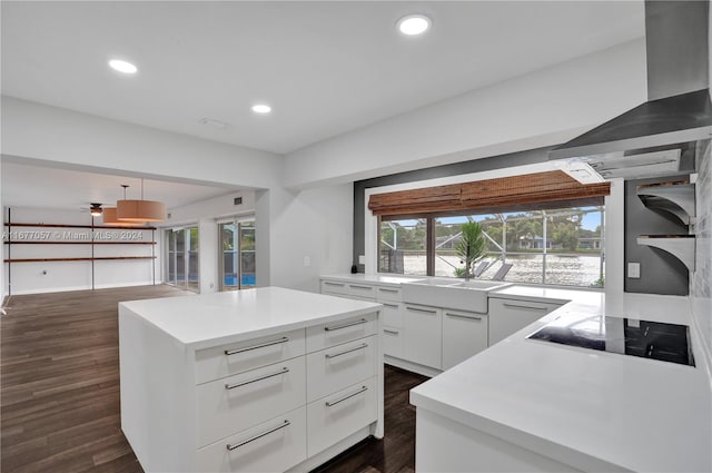 kitchen with black electric stovetop, a kitchen island, dark wood-type flooring, sink, and white cabinets