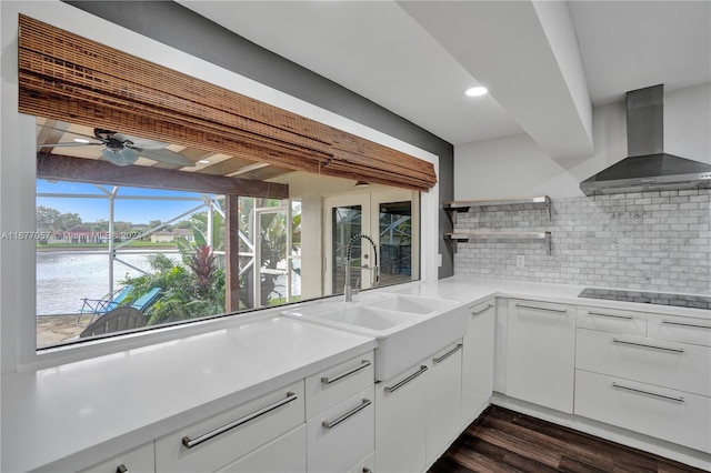 kitchen featuring a water view, wall chimney range hood, and white cabinets